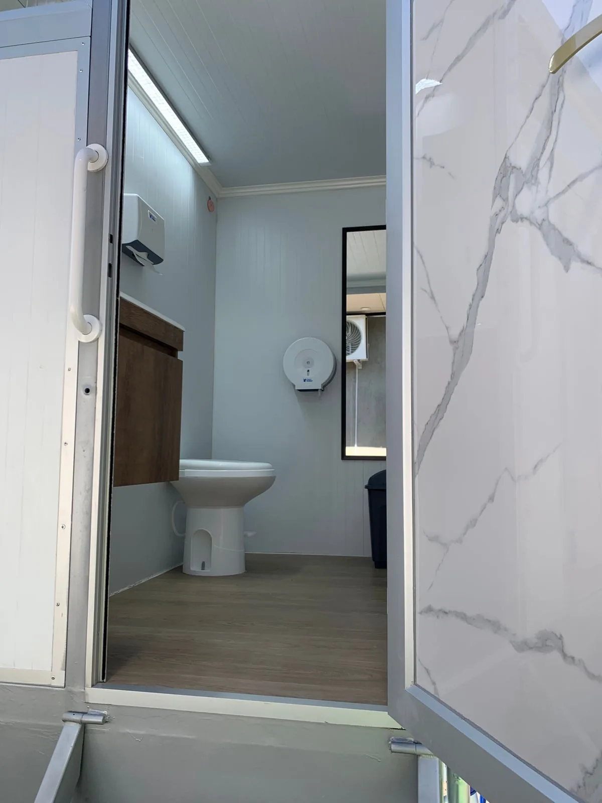 Interior del tráiler Maihue con vanity iluminado, espejo, jabón líquido y toallas foliadas