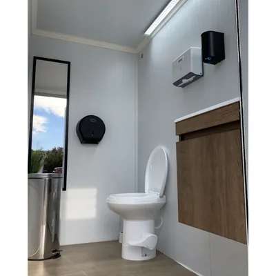Interior del baño móvil premium Maihue: inodoro, espejo de cuerpo entero, dispensador de papel y secador de manos
