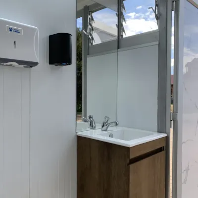 Interior del baño móvil Maihue con luz natural: lavamanos, grifería y ventana abierta