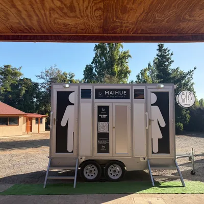 Tráiler de baños móviles Maihue instalado bajo una pérgola entre pinos, en una parcela