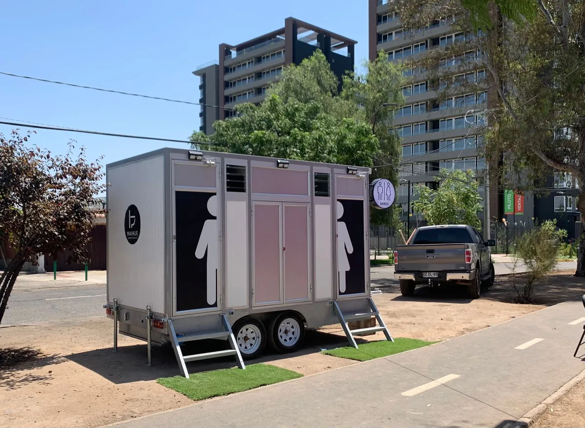 Tráiler de baños premium Maihue instalado en una calle de Santiago, con edificios de fondo